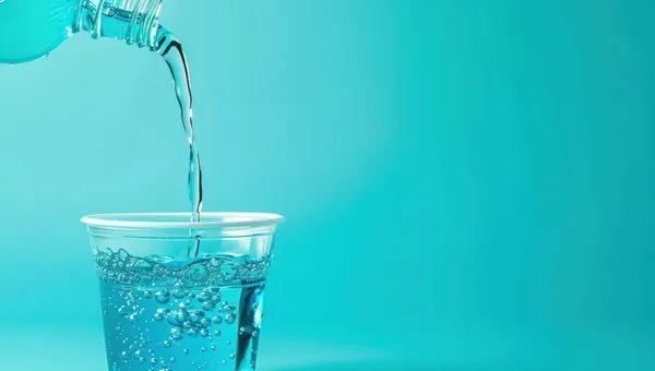 Niebieski płyn do płukania jamy ustnej wlewany do plastikowego kubeczka