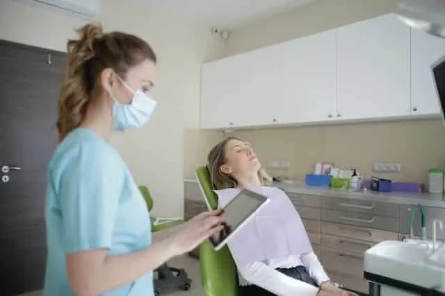 Pacjentka w fotelu dentystycznym i asystentka z tabletem w gabinecie