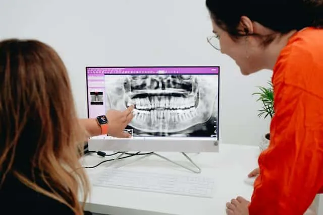 Dwie osoby oglądają zdjęcie pantomograficzne zębów na ekranie komputera