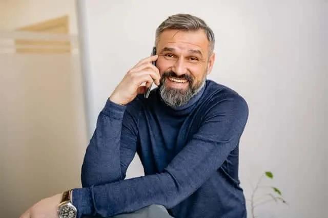 Uśmiechnięty dojrzały mężczyzna rozmawiający przez telefon