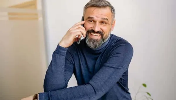 Uśmiechnięty dojrzały mężczyzna rozmawiający przez telefon