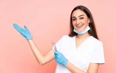 Uśmiechnięta dentystka w rękawiczkach trzyma narzędzie stomatologiczne